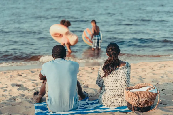 Parents regardant les enfants jouer en mer — Photo de stock