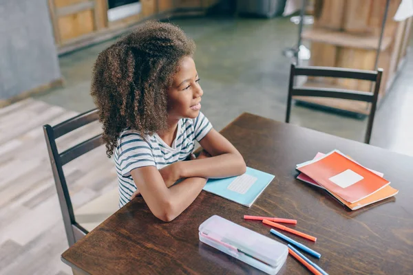 Little girl with school supplies at table — Stock Photo