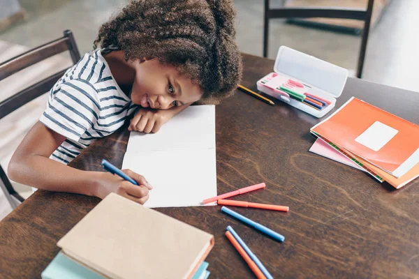 Petite fille écrivant dans un carnet — Photo de stock