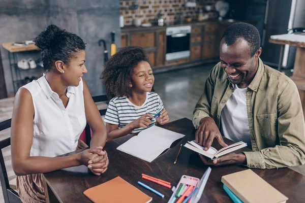 Chica y padres leyendo libro juntos - foto de stock