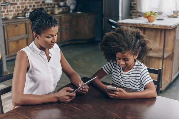 Girl and mother using smartphone and tablet — Stock Photo
