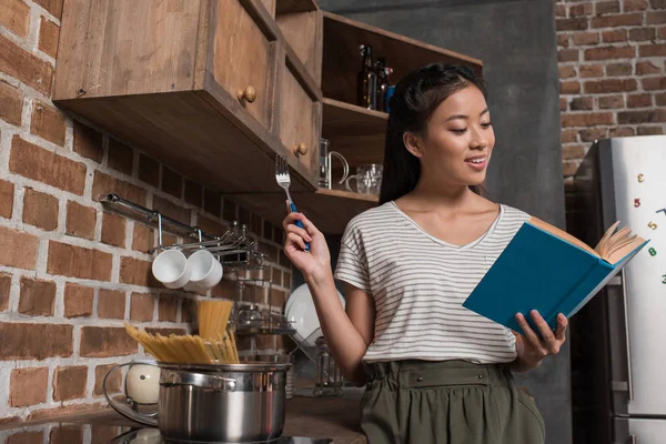 Estudante cozinhar e ler livro — Fotografia de Stock