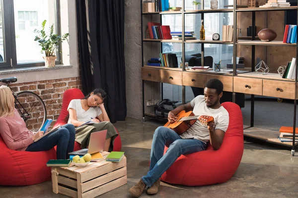 Meninas estudando enquanto estudante tocando guitarra — Fotografia de Stock