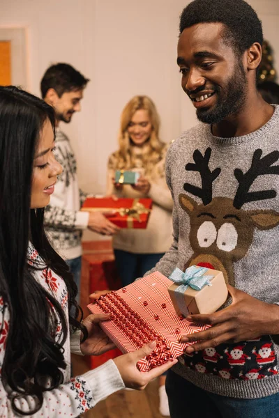Multiethnic couple exchanging christmas gifts — Stock Photo
