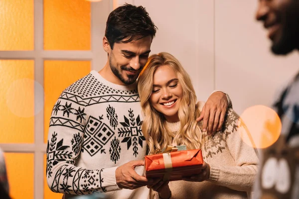 Casal feliz com presente em casa no Natal — Fotografia de Stock