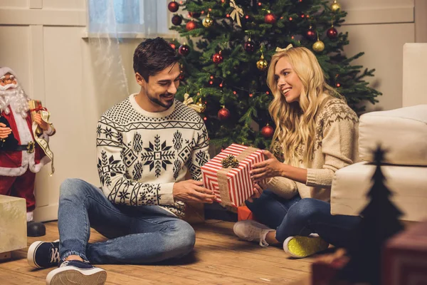 Casal feliz com presente em casa no Natal — Fotografia de Stock