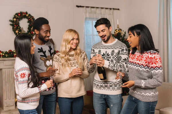 Amigos multiculturales con champán celebrando la Navidad - foto de stock