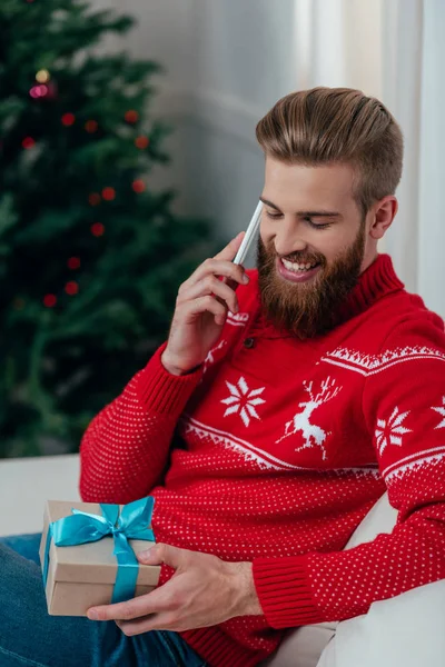 Man talking by phone and looking at gift — Stock Photo