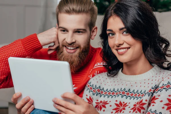 Пара в рождественских свитерах с помощью планшета — стоковое фото