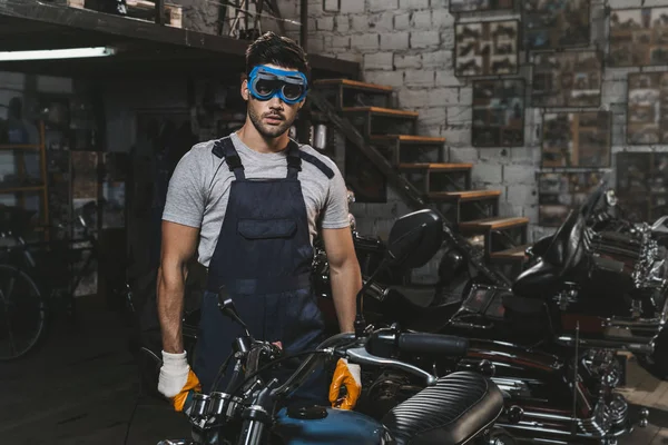 Repairman in goggles with motorcycle — Stock Photo