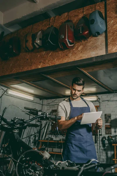 Trabalhador com tablet reparação de motocicleta — Fotografia de Stock