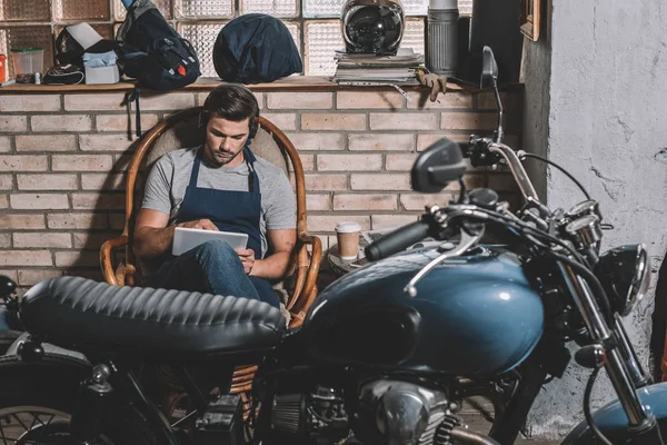 Automechanic with tablet in repair shop — Stock Photo