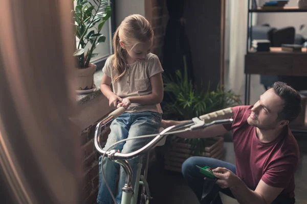 Hija sentada en bicicleta reparada - foto de stock