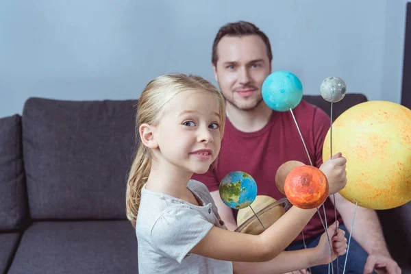 Отец и дочь позируют с планетами — стоковое фото