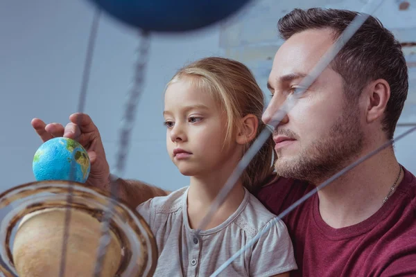 Father showing daughter model of Earth — Stock Photo