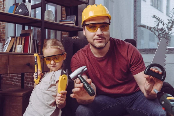 Padre e hija posando con herramientas plásticas - foto de stock