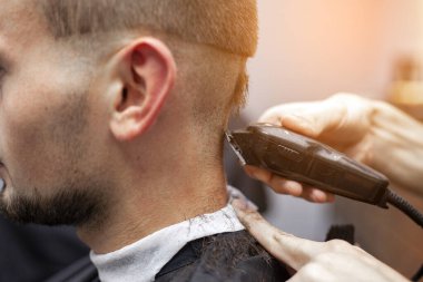 Genç adam bir berber dükkanında kısa bir saç kesimi yapıyor.