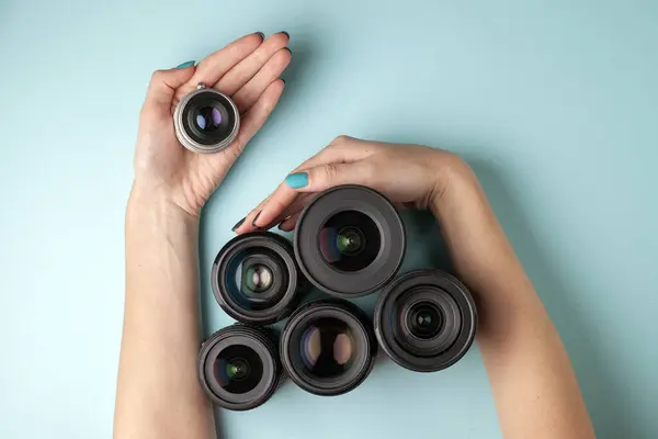 Conjunto de lentes fotográficas em um fundo colorido, a seleção e comparação de equipamentos fotográficos, as mãos estão segurando equipamento fotográfico — Fotografia de Stock