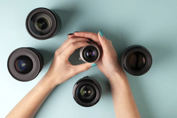 Conjunto de lentes fotográficas em um fundo colorido, a seleção e comparação de equipamentos fotográficos, as mãos estão segurando equipamento fotográfico — Fotografia de Stock