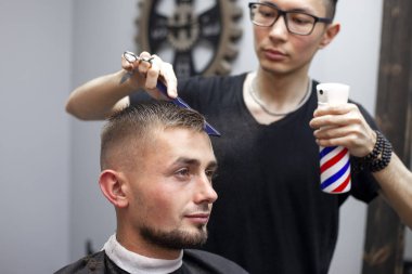 Kazak berber müşteriye kısa saç tıraşı yapar, berber dükkanında saç tıraşı olur, kuaförde saç stili yapar.