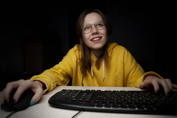 Menina gamer senta-se em um laptop à noite em casa, um estudante joga jogos, ela perde e ganha — Fotografia de Stock