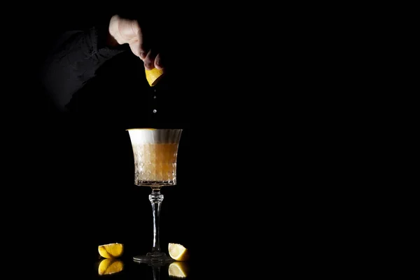 Bartender makes classic amber cocktail with citrus and ice on a black background — Stock Photo, Image