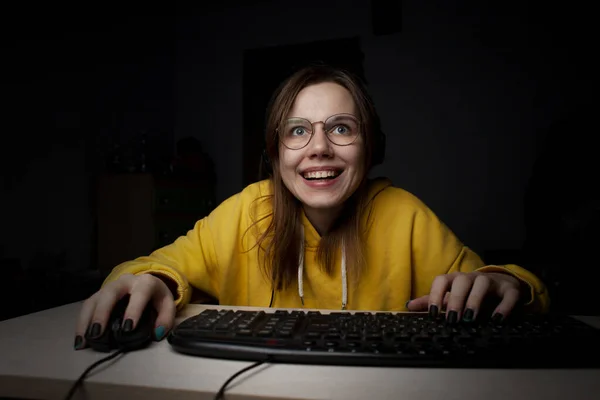 Menina gamer senta-se em um laptop à noite em casa, um estudante joga jogos, ela perde e ganha — Fotografia de Stock