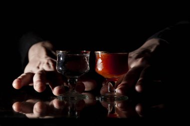 Barmen siyah bir arka planda tekila ve sangrit servis eder, elleri geceleri barda alkolü tutar.