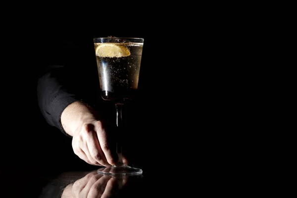 Barman faz um coquetel com champanhe em um copo em um fundo preto — Fotografia de Stock