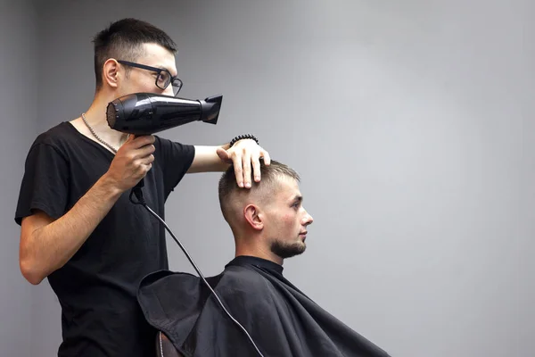 一个英俊的男人在理发店理发，一个哈萨克理发师干了头发 — 图库照片