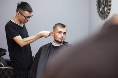 Kazak berber müşteriye kısa saç tıraşı yapar, berber dükkanında saç tıraşı olur, kuaförde saç stili yapar.