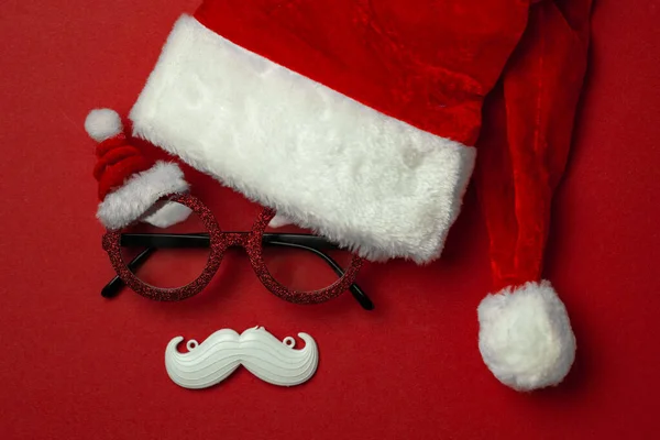 Fondo rojo de Navidad con gafas de Santa Claus y bigote hipster blanco. Símbolos de Navidad y decoraciones de Año Nuevo —  Fotos de Stock
