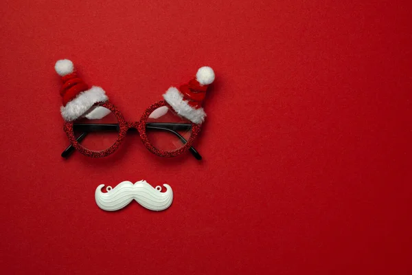 Fondo rojo de Navidad con gafas de Santa Claus y bigote hipster blanco. Símbolos de Navidad y decoraciones de Año Nuevo —  Fotos de Stock