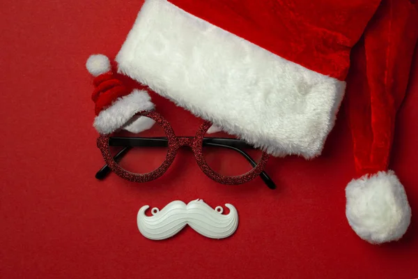 Fondo rojo de Navidad con gafas de Santa Claus y bigote hipster blanco. Símbolos de Navidad y decoraciones de Año Nuevo —  Fotos de Stock