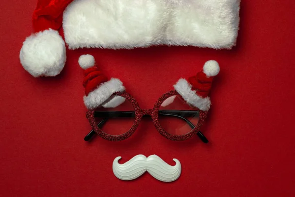 Fondo rojo de Navidad con gafas de Santa Claus y bigote hipster blanco. Símbolos de Navidad y decoraciones de Año Nuevo —  Fotos de Stock