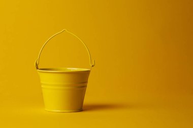 Sarı arka planda bahçıvanlık için sarı boş küçük kova, yaz konsepti, sebze bahçeleri mevsimi