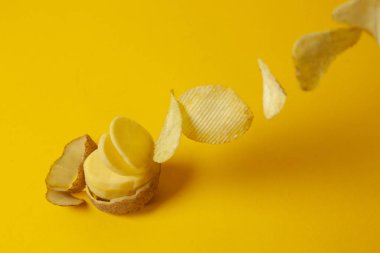 Patates cipsi sarı arka planda uçar, cips yapma süreci, fast food havalanması