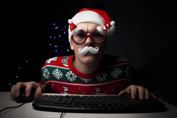 Adam yılbaşı gecesi bilgisayarda oynuyor. Noel 'de yalnız bir oyuncu bilgisayar başında oturuyor.