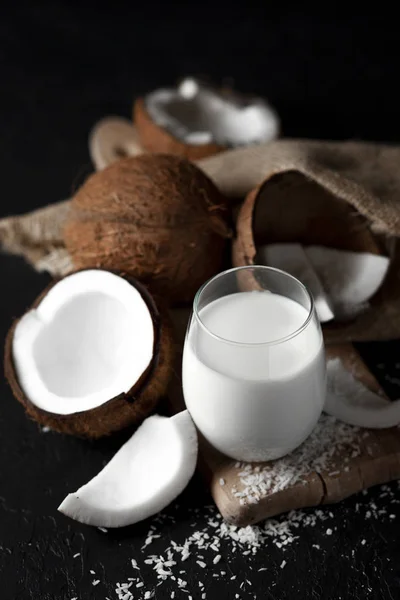 짙은 배경에 유리 안에 신선 한 코코넛 우유, 코코넛 화장품 크림, 코코넛 슬라이스와 함께 밀크 쉐이크 — 스톡 사진