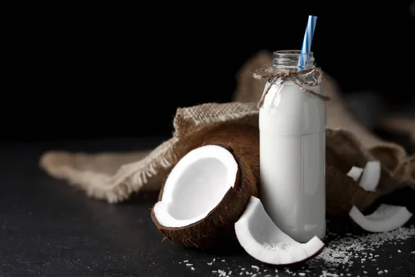 Frullato di cocco fresco naturale su fondo nero scuro, latte in bottiglia con ingredienti di cottura — Foto Stock