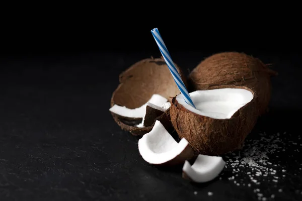 Milkshake de coco fresco natural em um fundo preto escuro, leite em um prato de coco — Fotografia de Stock