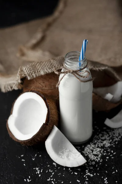 Frullato di cocco fresco naturale su fondo nero scuro, latte in bottiglia con ingredienti di cottura — Foto Stock