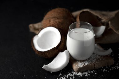 Bir bardakta taze hindistan cevizi sütü koyu bir arka plan, Hindistan cevizi kozmetik kreması, hindistan cevizi dilimli milkshake.