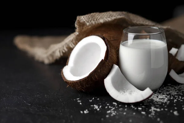 Latte di cocco fresco in un bicchiere su sfondo scuro, crema cosmetica al cocco, frullato con fette di cocco — Foto Stock