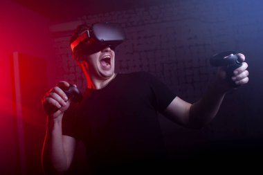 Kablosuz sanal gerçeklik gözlüklü bir adam karanlık bir odada tetikçiyi oynuyor, modern oyun alanı olan bir adam oyuna odaklanmış durumda.