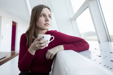 Genç ve güzel bir kız sabah bir kafede kahve içer ve pencereden dışarı bakar, bir öğrenci kahvaltı yapar ve şehre bakar.