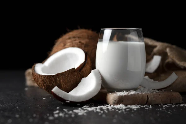 Latte di cocco fresco in un bicchiere su sfondo scuro, crema cosmetica al cocco, frullato con fette di cocco — Foto Stock