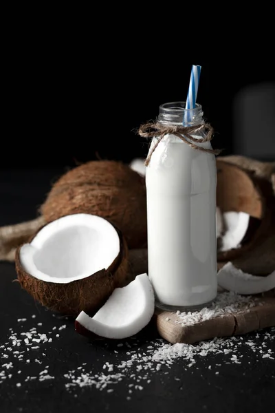 Latte di cocco fresco in bottiglia su sfondo scuro, frullato di cocco su un tavolo nero — Foto Stock