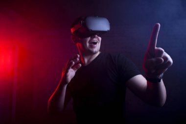 Sanal gerçekliğin modern gözlüklü bir adam karanlık bir arka plana karşı, bir adam sanal dünyaya dokunuyor.