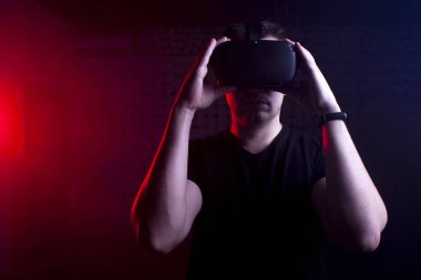 Modern kablosuz sanal gerçeklik gözlüklü bir adam karanlık bir arka plana karşı, bir adam sanal dünyaya dokunuyor.